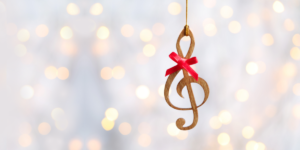 A wooden music note ornament with a red bow on it. The background is white with sparkling Christmas lights