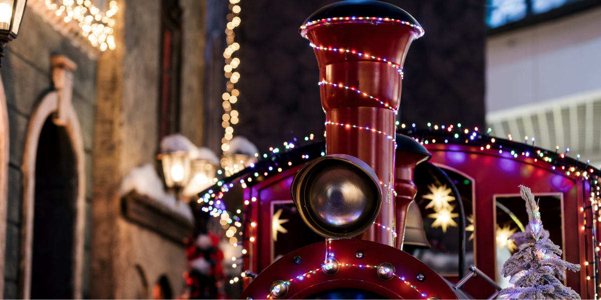 The top front of a red Christmas train covered in Christmas decoration and lights.