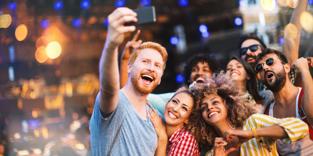 A group of friends taking a selfie together at an outdoor music festival